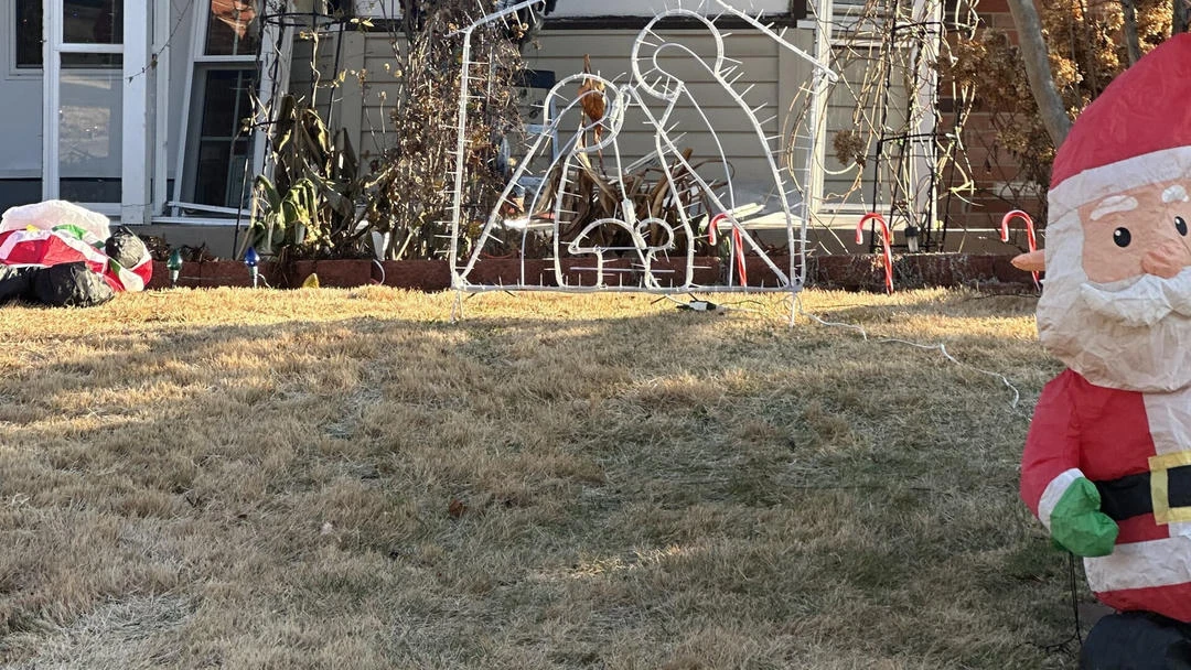 Christmas nativity scene, two candy canes, and an inflatable Santa Claus on a dry grass lawn.